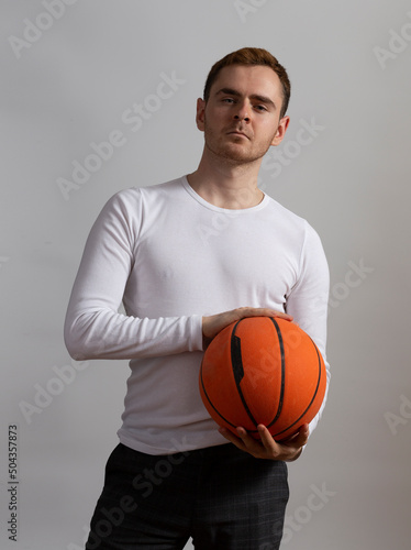 Contemporary young man poses in studio.with a basketball.