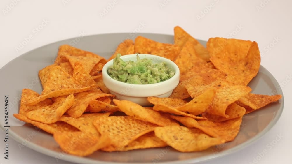 Female hand dipping nachos in guacamole sauce Female hand dipping nachos in guacamole sauce