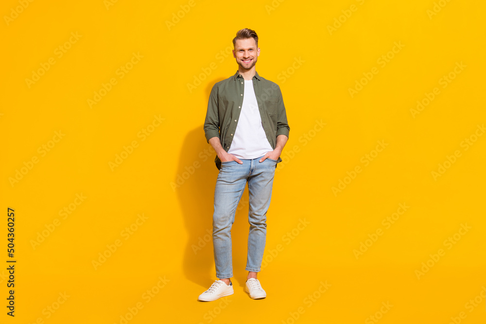 Full length body size view of attractive cheerful content guy posing isolated over vibrant yellow color background Full length body size view of attractive cheerful content guy posing isolated over vibrant yellow color background