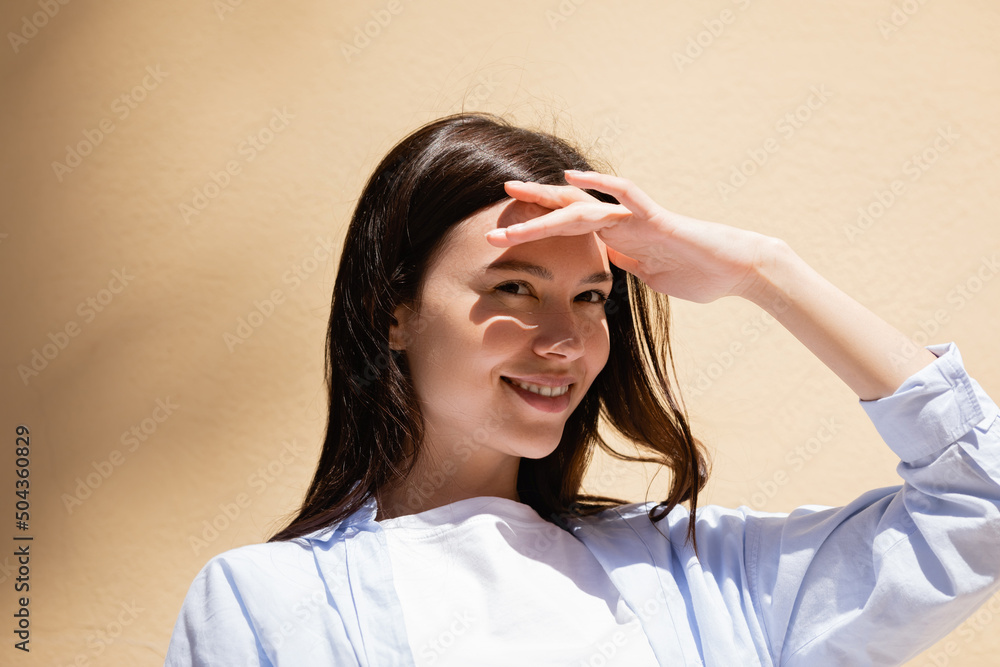 cheerful brunette woman holding hand above eyes and looking away outdoors. cheerful brunette woman holding hand above eyes and looking away outdoors.