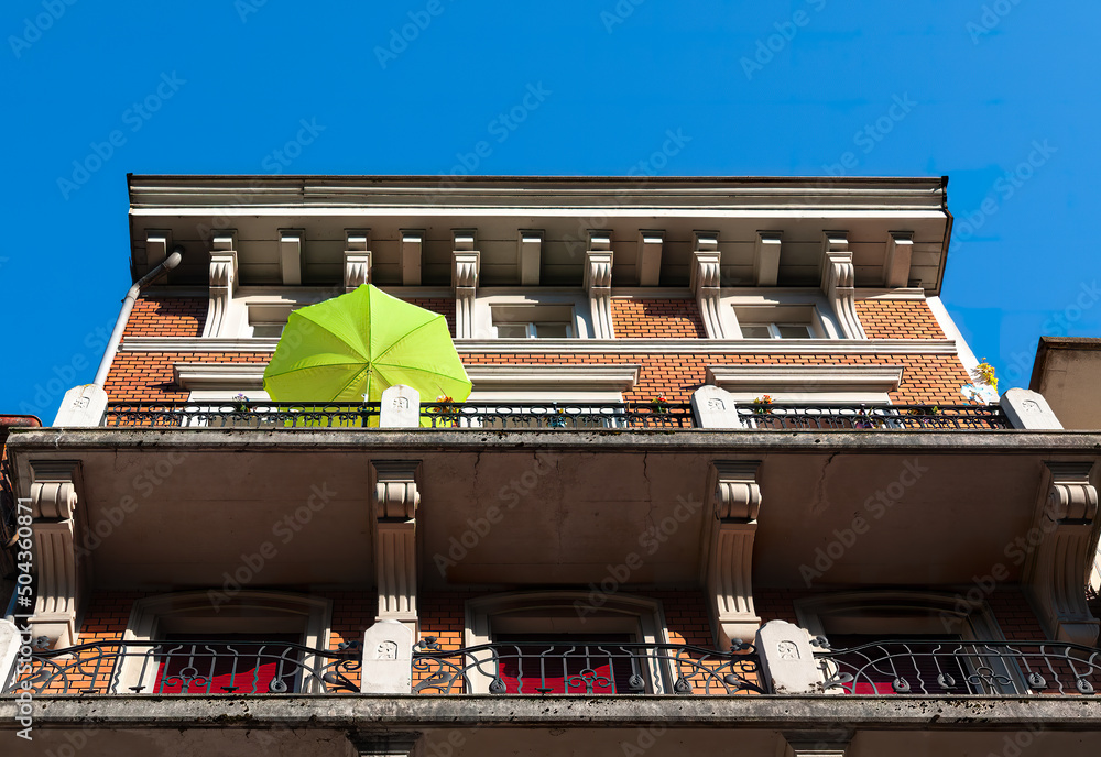 Biel, Switzerland - Mai 11, 2022: Low angle view of old historic house in Biel with a green sunny umbrella on the balcony