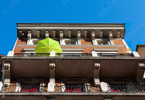 Biel, Switzerland - Mai 11, 2022: Low angle view of old historic house in Biel with a green sunny umbrella on the balcony photo