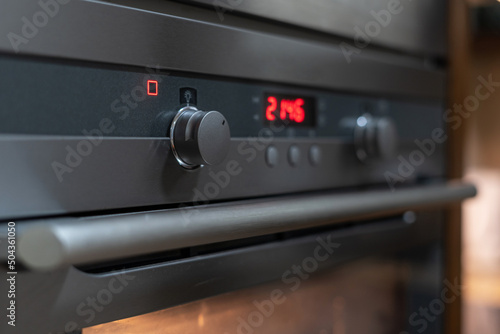 Modern grey oven showing time in digital numbers