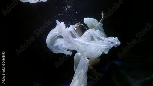 Surreal mermaid underwater on the surface. A majestic female aquatic creature. art installation under water