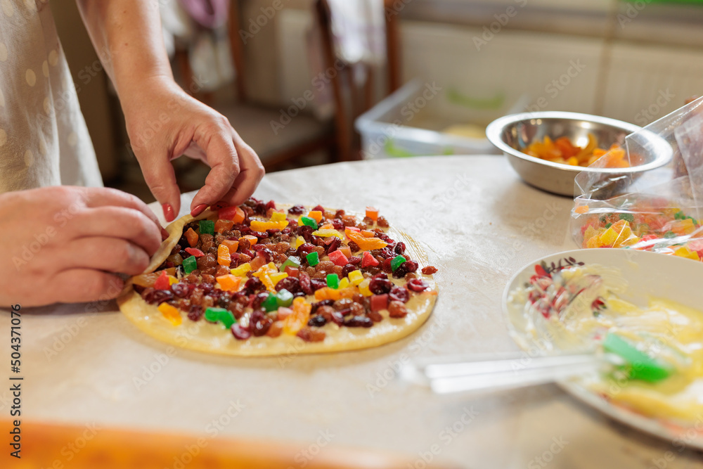 female hands twist the dough with raisins and candied fruits. raw cake dough female hands twist the dough with raisins and candied fruits. raw cake dough