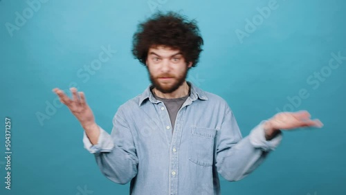 Young bearded guy shows hands gesture making person guess photo