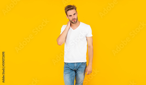 man with bristle in white shirt. young man with beard on yellow background.