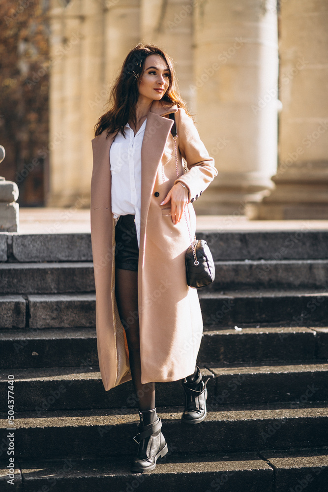 Pretty woman in beige coat outside the university Pretty woman in beige coat outside the university