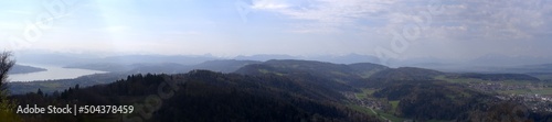 Wide angle panoramic view from local mountain Uetliberg with Lake Zürich and Swiss Alps in the background on a blue cloudy spring day. Photo taken April 14th, 2022, Zurich, Switzerland. © Michael Derrer Fuchs
