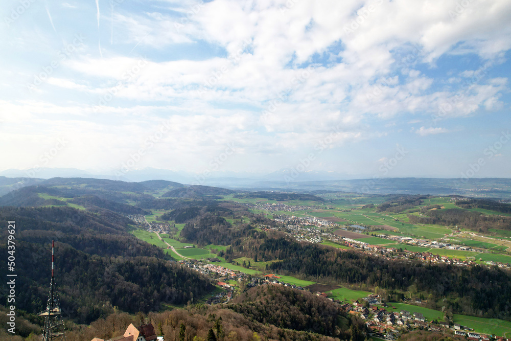 Obraz premium Aerial view of valley with forest and agricultural fields seen from local mountain Uetliberg on a blue cloudy spring day. Photo taken April 14th, 2022, Zurich, Switzerland.