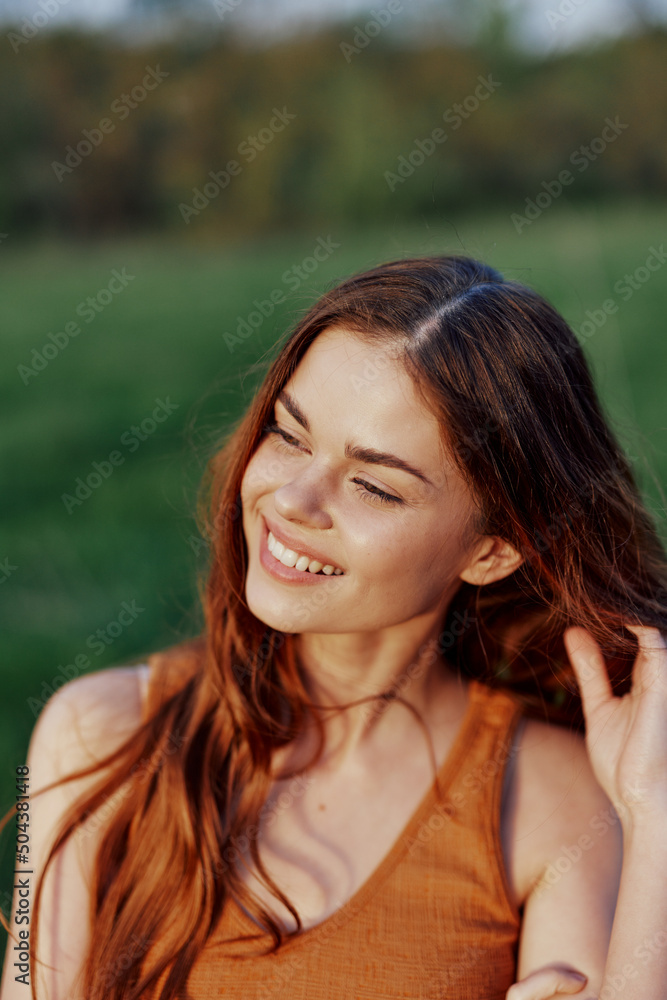 A beautiful redheaded woman laughs and smiles with her teeth in the bright sunset sunlight. The concept of healthy living and good nutrition A beautiful redheaded woman laughs and smiles with her teeth in the bright sunset sunlight. The concept of healthy living and good nutrition