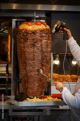 Traditional Turkish food Doner Kebab. The chef cut the beef meat from grilled roll on the street.