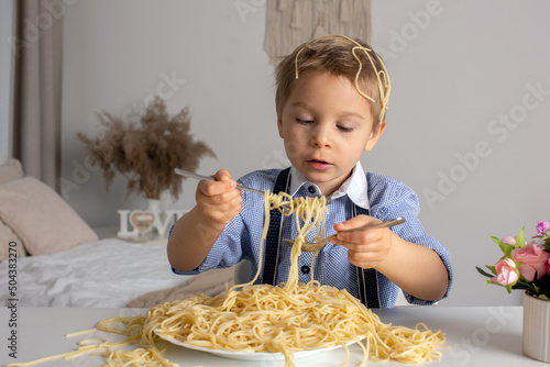 Cute preschool child  blond boy  eating spaghetti at home  making a mess everywhere