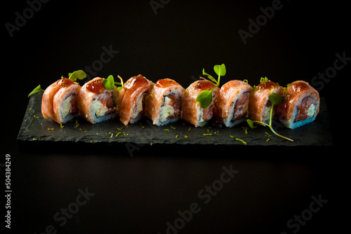 Sushi Set nigiri and sushi rolls on wooden serving board with soy sauce and chopsticks over black stone texture background. Delicious sushi set