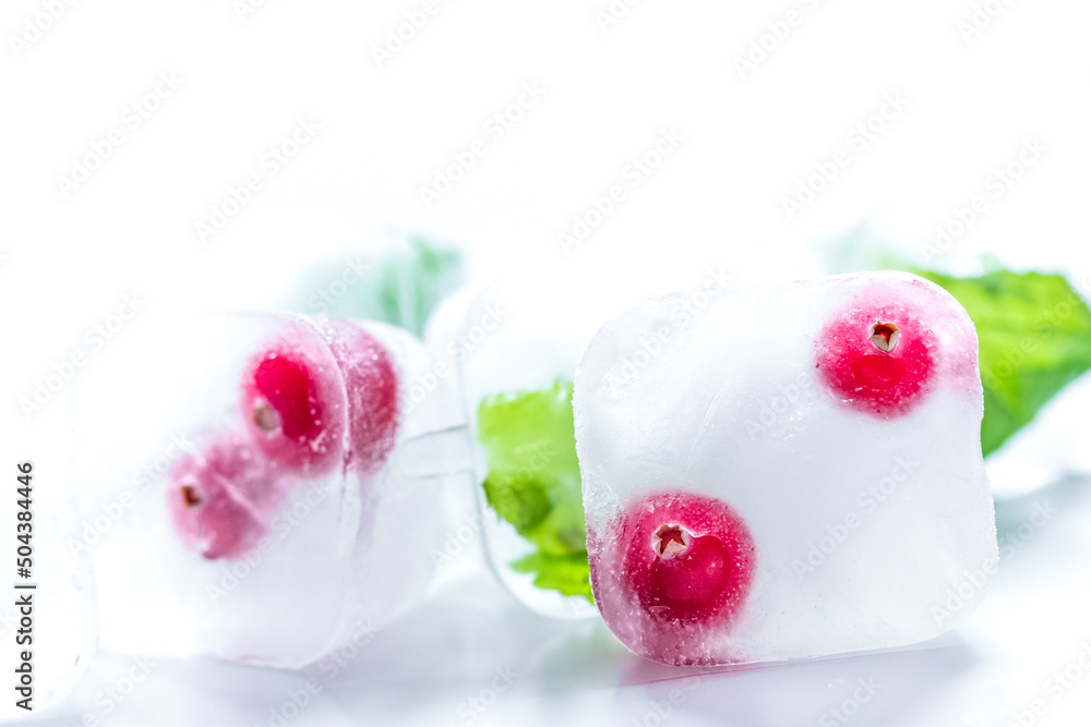 frozen red berries in ice cubes with mint on stone background frozen red berries in ice cubes with mint on stone background
