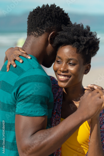 Close-up of smiling african american young woman with short hair dancing with boyfriend at beach