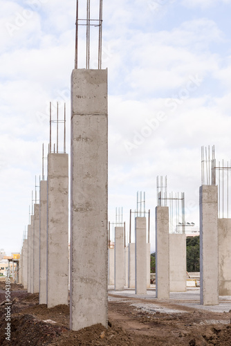 construction of an industrial building site with a line of concrete columns and reinforcing steel