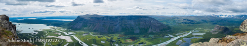 Aerial ultra wide panoramic scenic view from Skierffe rock summit, glacial Rapadalen river delta valley at Sarek national park with meanders, mountains, birch trees. Summer landscape Sweden Lapland