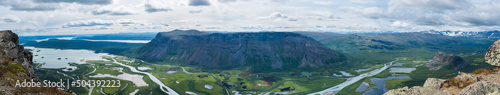 Aerial ultra wide panoramic scenic view from Skierffe rock summit  glacial Rapadalen river delta valley at Sarek national park with meanders  mountains  birch trees. Summer landscape Sweden Lapland