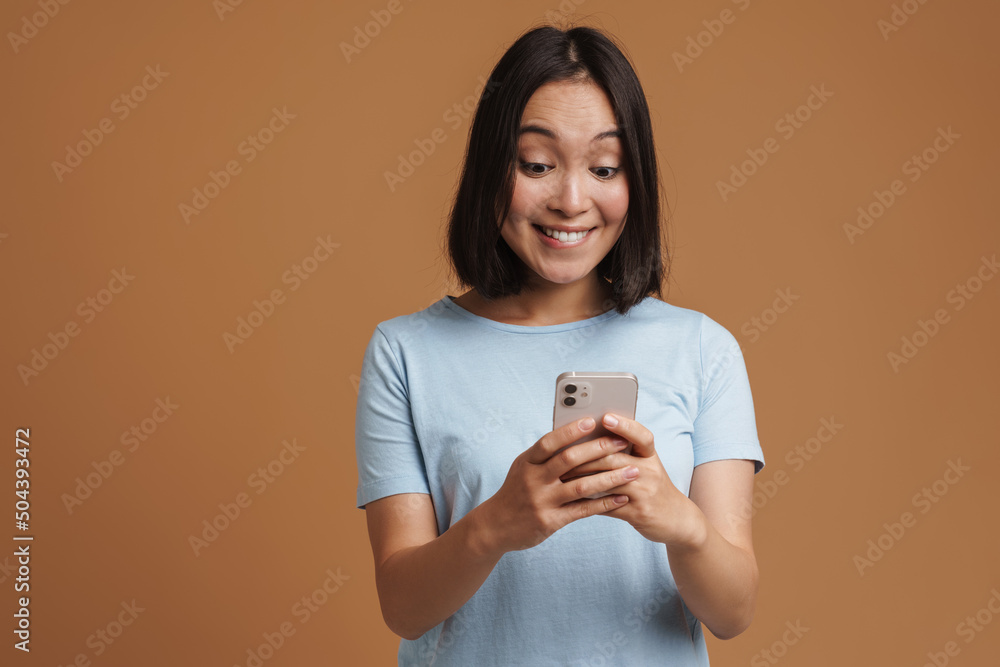 Young asian woman wearing t-shirt laughing while using mobile phone Young asian woman wearing t-shirt laughing while using mobile phone