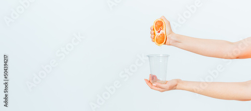 Female hands squeezing juice from fresh grapefruit
