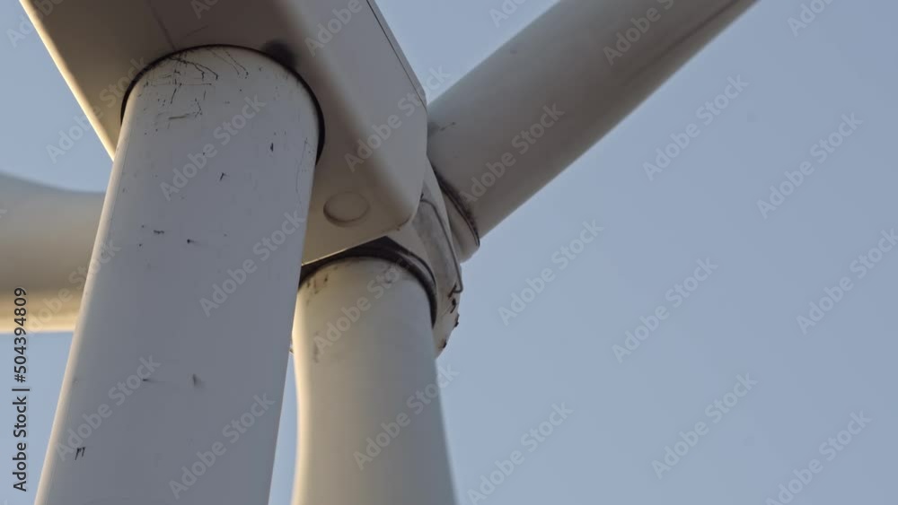 Close up shot of wind turbine power station from below. Environmental engineering and renewable energy. Scenic view of windmills turbine with blue sky in the evening with telephoto lens at golden hour Close up shot of wind turbine power station from below. Environmental engineering and renewable energy. Scenic view of windmills turbine with blue sky in the evening with telephoto lens at golden hour