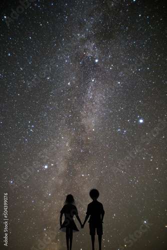 天の川と満天の星空を見つめる手を繋いだカップルのシルエット。夏の恋のコンセプト。 photo