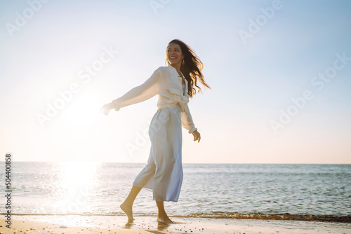 Young  woman walking in the sunset on the beach.. Summer time. Travel, weekend, relax and lifestyle concept.