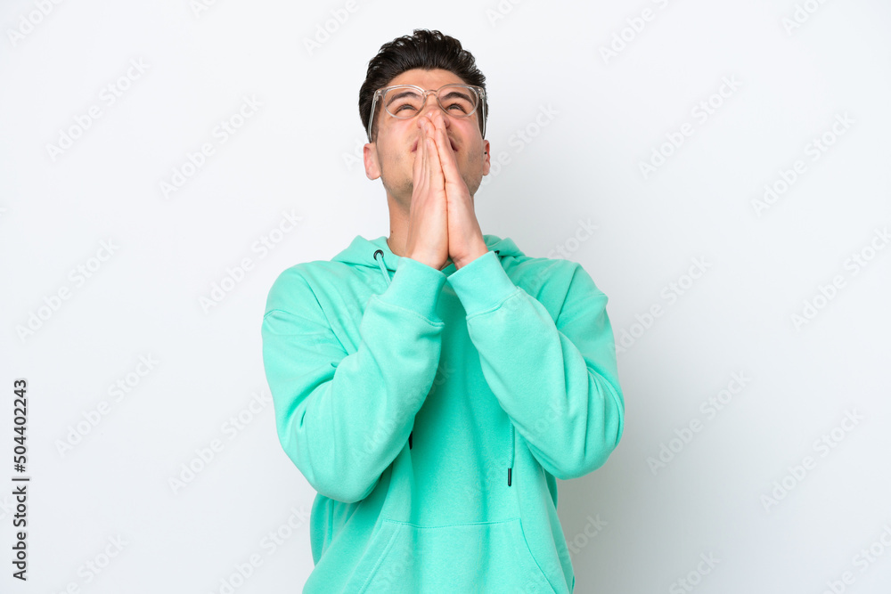 Young handsome caucasian man isolated on white bakcground keeps palm together. Person asks for something Young handsome caucasian man isolated on white bakcground keeps palm together. Person asks for something