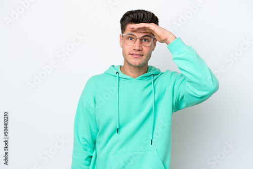 Young handsome caucasian man isolated on white bakcground looking far away with hand to look something