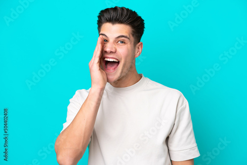 Young handsome caucasian man isolated on blue bakcground with surprise and shocked facial expression
