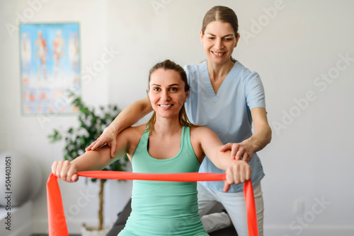 Modern rehabilitation physiotherapy woman worker with woman client using elastic