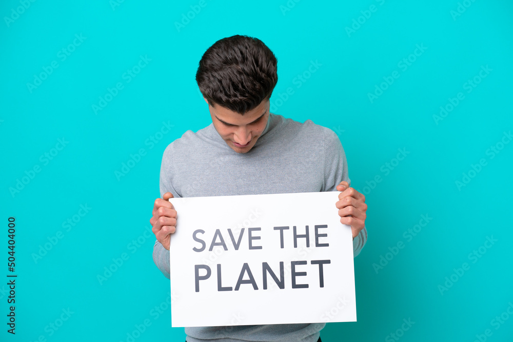 Young handsome caucasian man isolated on blue bakcground holding a placard with text Save the Planet Young handsome caucasian man isolated on blue bakcground holding a placard with text Save the Planet