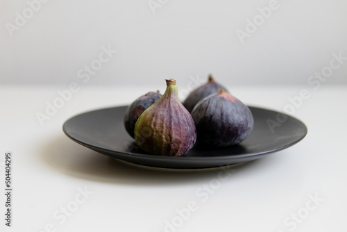 Figs on a light background on a black plate.