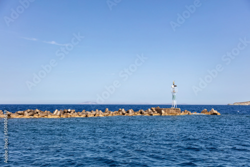 Beacon at breakwater concrete block at Ermoupolis city port, Syros island, Cyclades Greece.