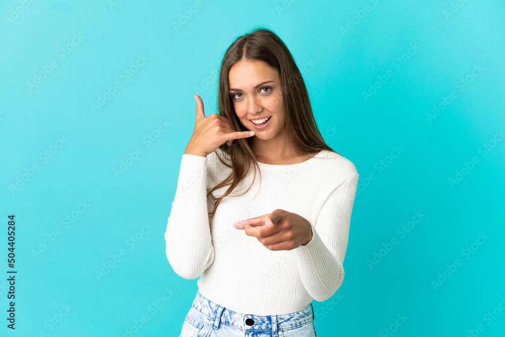 Fototapeta premium Young woman over isolated blue background making phone gesture and pointing front