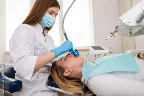The dentist makes a professional cleaning of the teeth of a young female patient in the dental office.
