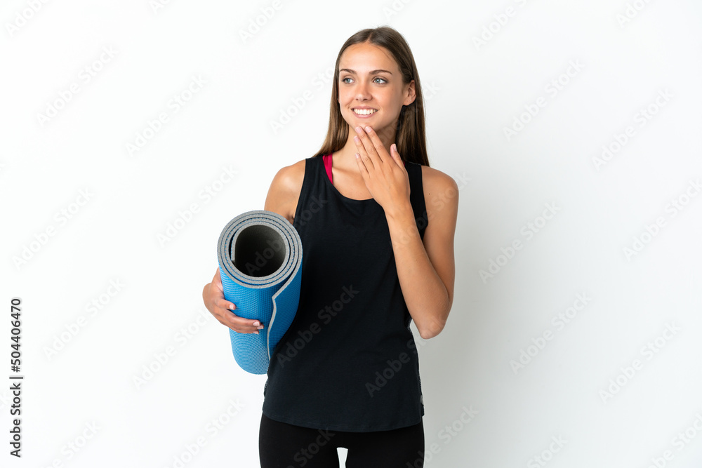 Sport woman going to yoga classes while holding a mat over isolated white background looking up while smiling Sport woman going to yoga classes while holding a mat over isolated white background looking up while smiling