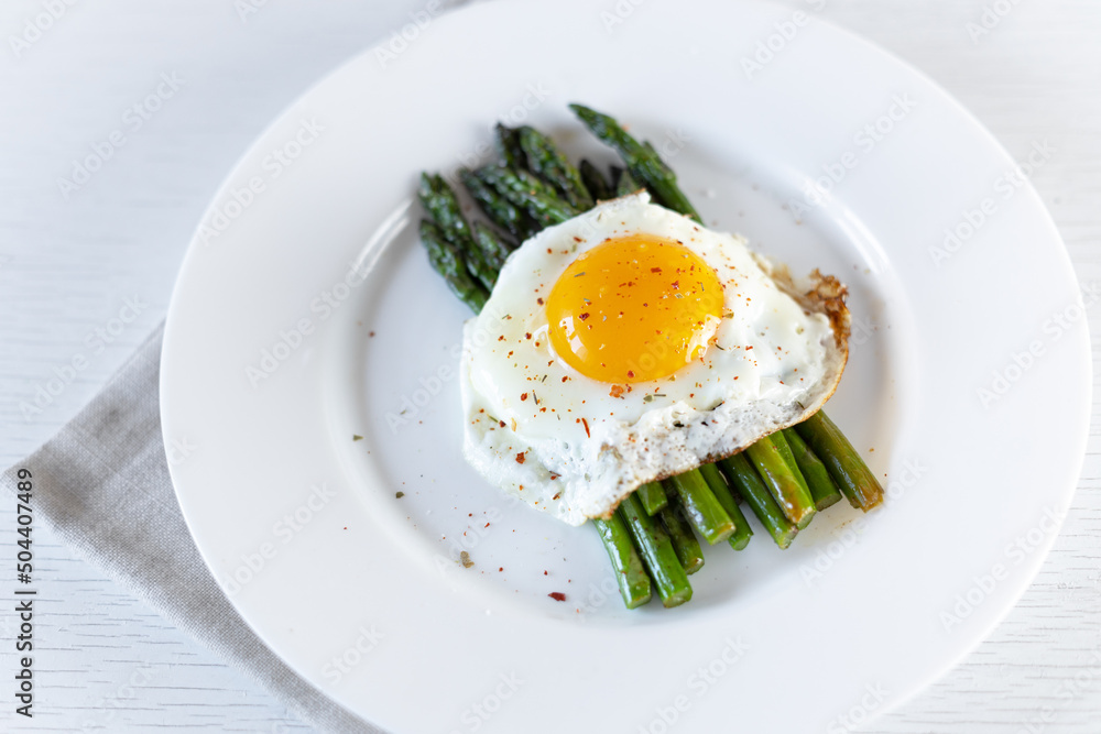 Cooking asparagus. Fried asparagus sprouts and fried eggs on a white plate. Healthy food and diet. Cooking asparagus. Fried asparagus sprouts and fried eggs on a white plate. Healthy food and diet.