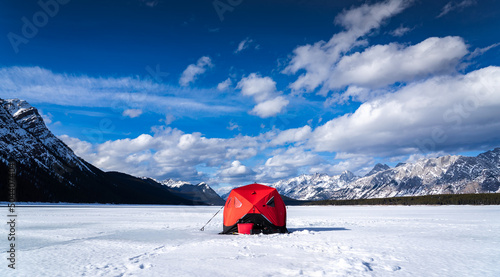 An ice fishing tent for trout fishing standing tall on a frozen lake in the Canadian Rocky Mountains in Kananaskis Provincial Park Alberta.