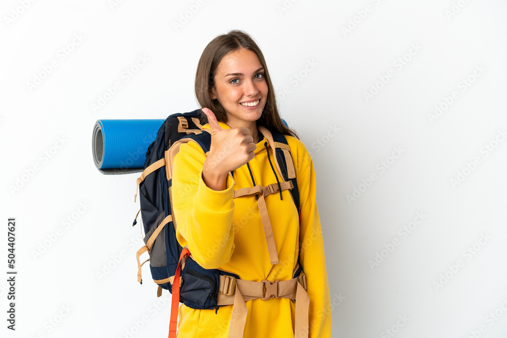 Young mountaineer woman with a big backpack over isolated white background with thumbs up because something good has happened Young mountaineer woman with a big backpack over isolated white background with thumbs up because something good has happened