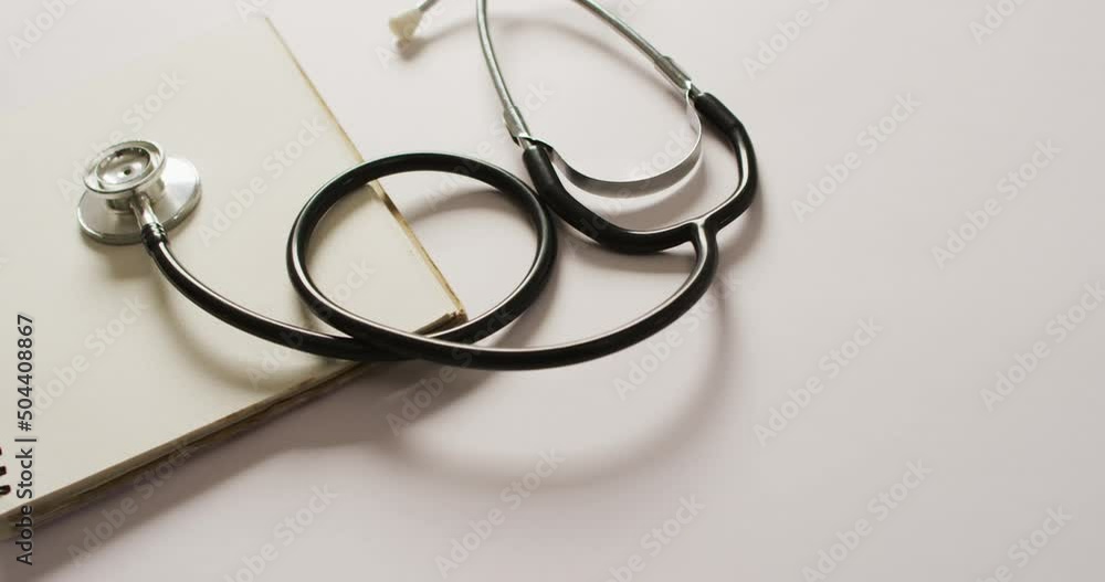 Video of close up of stethoscope with notebook on pink background Video of close up of stethoscope with notebook on pink background
