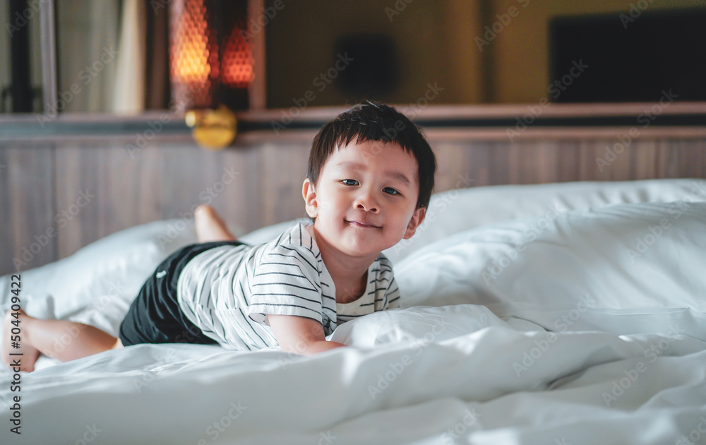 Portrait of Little boy wear striped shirt feel relax and laydown on the bed, looking at camera. A caucasian kid feel comfortable lying down on the bed with smiling face. Bed Vibes concept. Happy Kids. Portrait of Little boy wear striped shirt feel relax and laydown on the bed, looking at camera. A caucasian kid feel comfortable lying down on the bed with smiling face. Bed Vibes concept. Happy Kids.