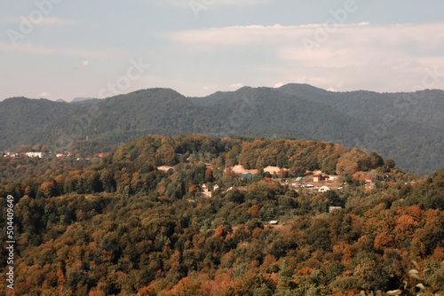 Hilly mountains covered with forests with colorful houses