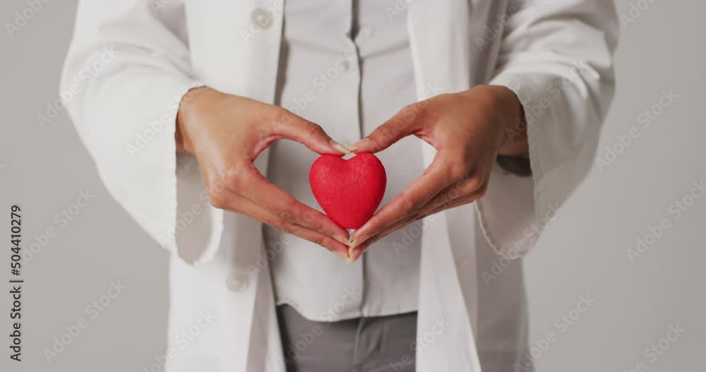 Video of biracial female doctor holding heart on white background Video of biracial female doctor holding heart on white background