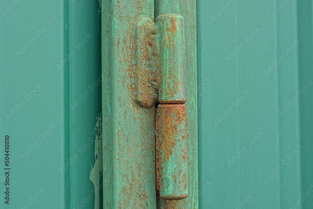 one iron green door hinge in rust on a metal gate on a wall in the street one iron green door hinge in rust on a metal gate on a wall in the street