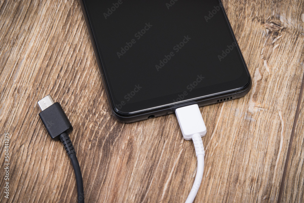 Smartphone with charger cables. Telephone charging concept Smartphone with charger cables. Telephone charging concept