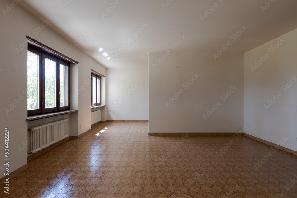 Front view room with dirty white walls and brown tiles. Interior of empty old villa to be refurbished Front view room with dirty white walls and brown tiles. Interior of empty old villa to be refurbished