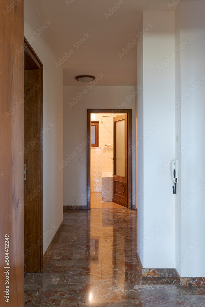Front view corridor with an open door to the bathroom at the end. Interior of empty old villa to be refurbished