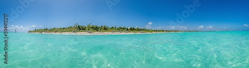 Panorama over a tropical beach taken from the water during the day with sunshine